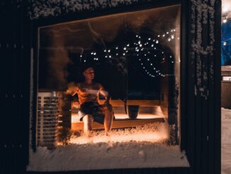 Person sitter i en varm bastu omgiven av snö och vintermörker