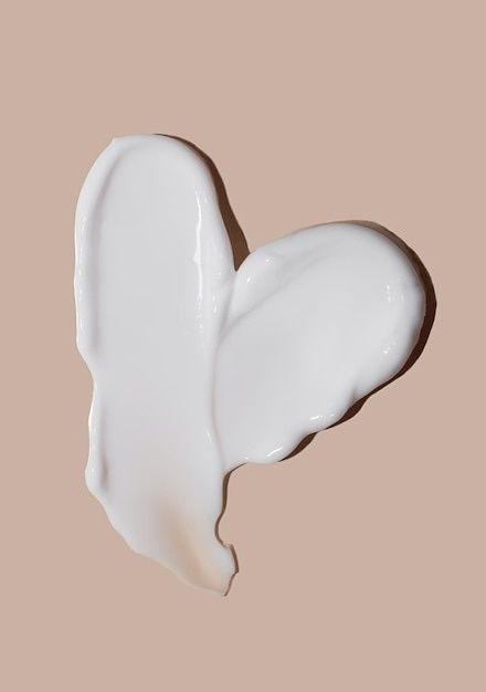 Vit, blank hudkräm utbredd i en mjuk fjärilsform på beige bakgrund