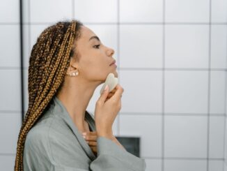 Kvinna använder en gua sha-sten längs käklinjen och halsen